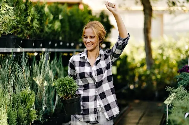 可愛い服を着た綺麗な女性が、温室で植物に手を伸ばしている。